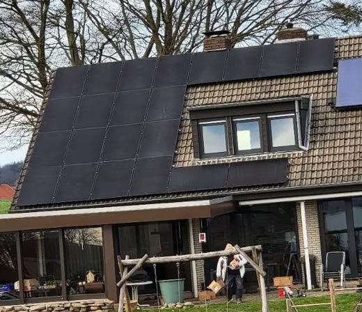 Hausdach mit dunklen Solarmodulen und Dachfenstern.